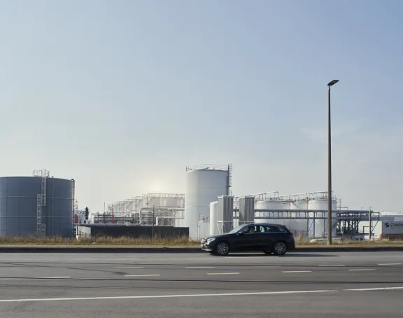 Car driving past the Schelde canal and storage tanks in the Port of Antwerp