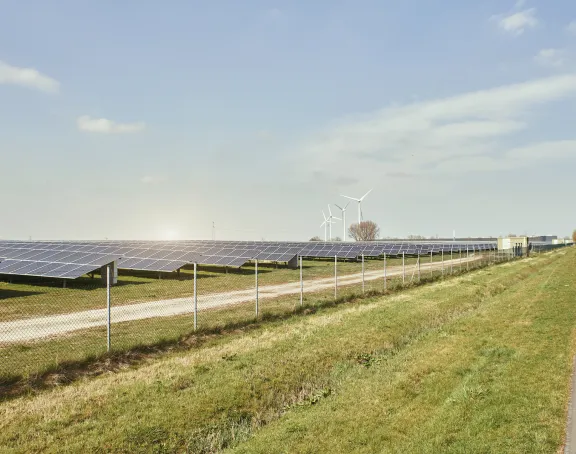 Solar panels and wind turbines on a green field