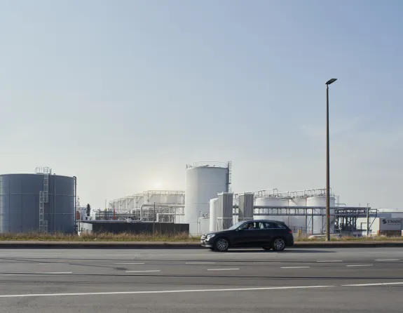 Car driving past the Schelde canal and storage tanks in the Port of Antwerp